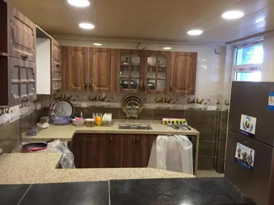 a kitchen with wooden cabinets and a sink and a refrigerator at asfouer Hostel in Muqbilah