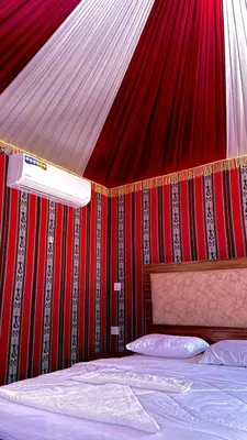 a bedroom with a red wall with a bed and a canopy at Nova Luxury Camp in Wadi Rum