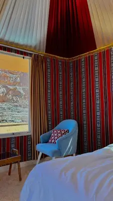 a bedroom with a bed and a blue chair at Nova Luxury Camp in Wadi Rum