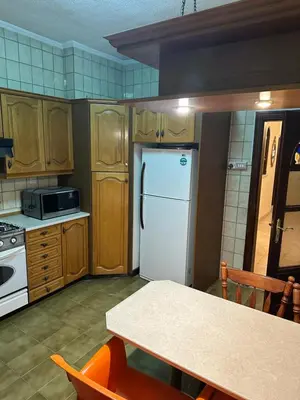 a kitchen with a white refrigerator and a table at University Castle in Amman