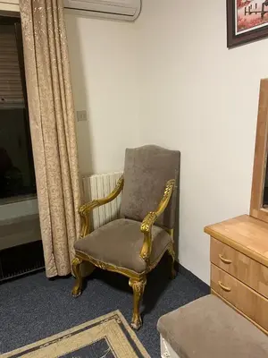 a chair sitting in a room next to a dresser at University Castle in Amman