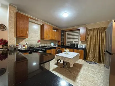 a kitchen with wooden cabinets and a table in it at zainab bedouin house in Petra
