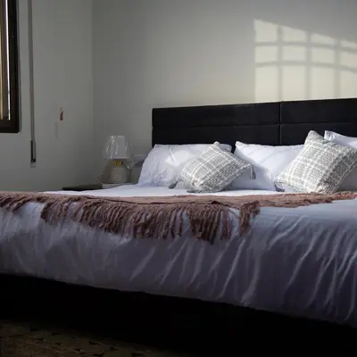 a bed with white sheets and pillows on it at LeRose Villa in Ash Shāghūr