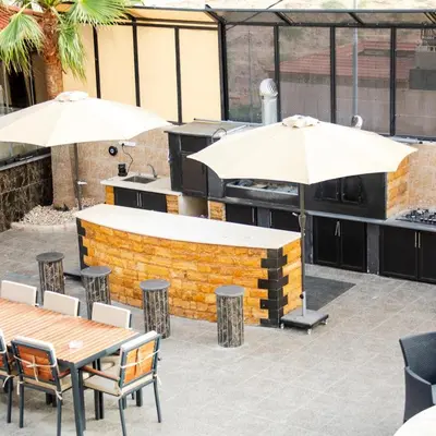 an outdoor bar with tables and umbrellas at LeRose Villa in Ash Shāghūr