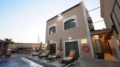 a building with a patio with chairs and a pool at LeRose Villa in Ash Shāghūr