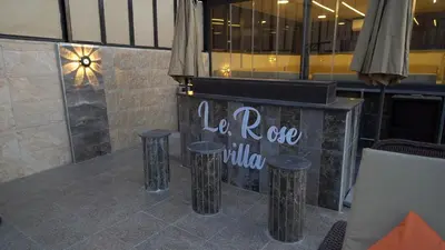 a table with stools in front of a restaurant at LeRose Villa in Ash Shāghūr