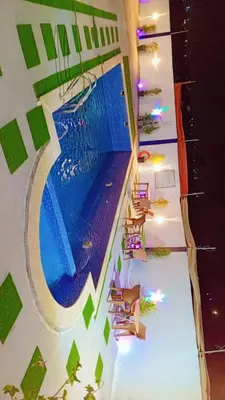 a swimming pool in a building with lounge chairs at Sky Blue Farm in Umm Jawzah