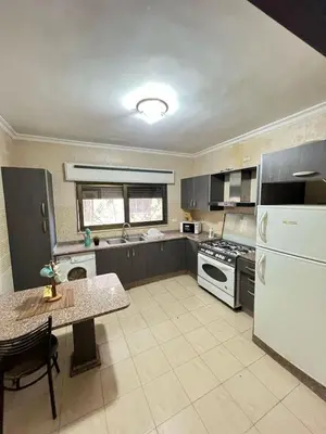 a kitchen with a white refrigerator and a table at On the street 3 Room in Amman