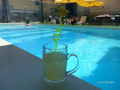 a drink in a cup next to a swimming pool at Firuza Farm Villa Vip in Al Rama