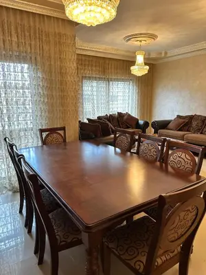 a dining room with a large wooden table and chairs at shafa badran شفا بدران ام الحجير in Amman