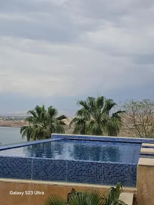 a swimming pool with palm trees and a body of water at C04 Samarah Resort One Bedroom apartment in Sowayma