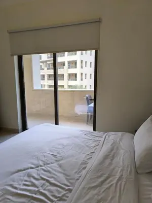 a white bed in a room with a large window at C04 Samarah Resort One Bedroom apartment in Sowayma