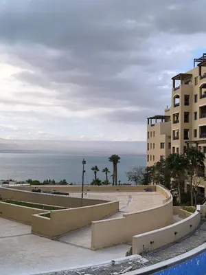 a view of a building with the ocean in the background at C04 Samarah Resort One Bedroom apartment in Sowayma
