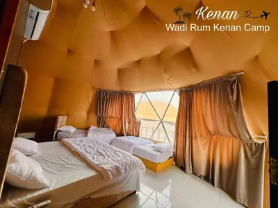a bedroom with two beds and a large window at Wadi Rum Kenan Camp in Wadi Rum