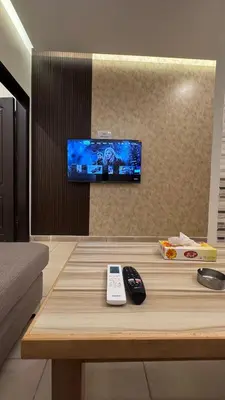 a table with a remote control and a tv on a wall at يزن للاجنحة الفندقية in Aqaba