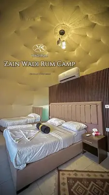 two beds in a hotel room with avertisement for at Zain Wadi Rum Camp in Wadi Rum