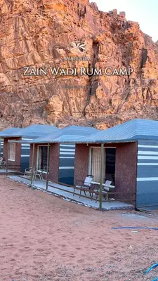 a building with a blue roof in front of a mountain at Zain Wadi Rum Camp in Wadi Rum