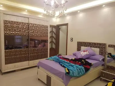 a bedroom with a large bed and a chandelier at VOV House in At-Tafilah