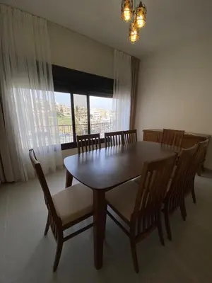 a dining room with a table and chairs and a window at Modern 2BR in Trendy Jabal AlWebdeh with View in Amman