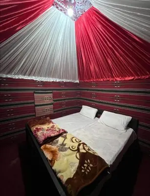 a bedroom with a bed in a red tent at Wadi Rum safari camp in Wadi Rum