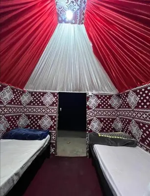 a red and white tent with two beds in it at Wadi Rum safari camp in Wadi Rum