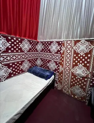 a bed in a room with red and white curtains at Wadi Rum safari camp in Wadi Rum