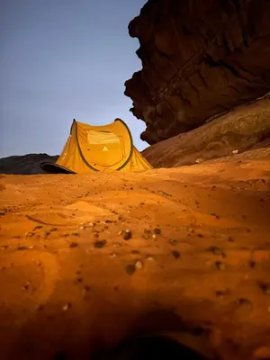 a person sitting in a desert with a yellow tent at Wadi Rum Sunrise Guesthouse in Wadi Rum