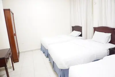 a hotel room with two beds and a desk at النخيل للشقق الفندقية ALnakheel hotel apartment in Aqaba