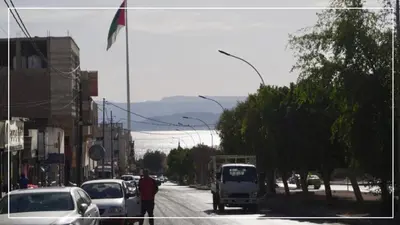 a man walking down a busy city street with cars at النخيل للشقق الفندقية ALnakheel hotel apartment in Aqaba