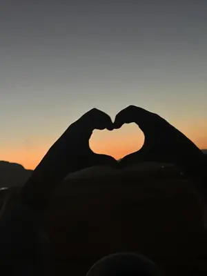 a pair of hands forming a heart at sunset at Gakleen luxury camp in Aqaba