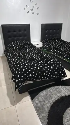 a bedroom with two beds with black and white comforter at Bonuk House in Kufayrāt Abū Khīnan