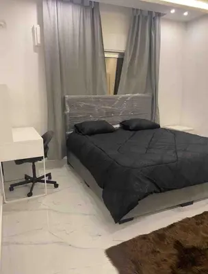 a bedroom with a black bed with a desk and a window at Cozy, Newly Furnished & Budget Friendly Apartment in Amman