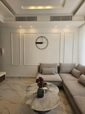 a living room with a couch and a clock on the wall at Shamsi Apartments 008 in Amman