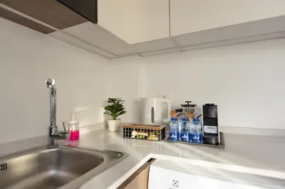 a kitchen counter with a sink and some bottles of water at Shamsi Apartments 008 in Amman