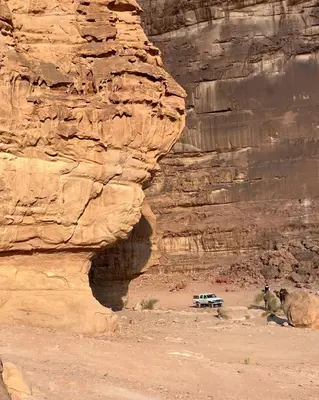 a jeep parked in the desert next to a cliff at Wadi rum Mahmoud tours in Wadi Rum