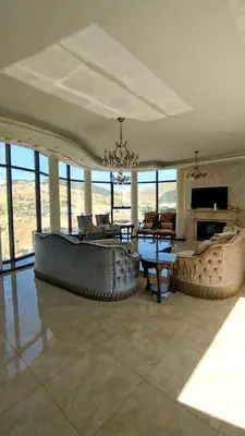 a living room with a large couch and a table at منتجع وفيلا تل الرمان in Ar Rummān