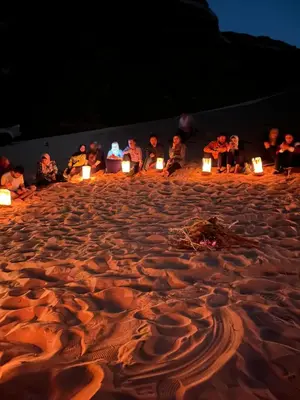 a group of people sitting in the sand with candles at Faraj wadi rum in Disah