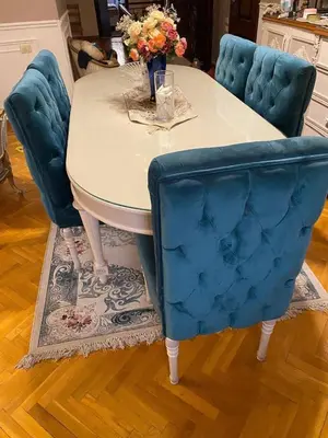 a table with two blue chairs and a table with flowers at عبق التاريخ هاوس in Rujm al Ḩāwī