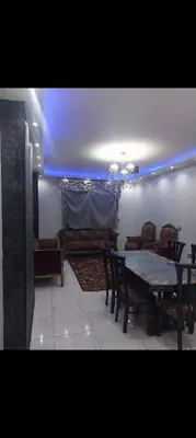 a dining room with a table and chairs and a blue light at عبق التاريخ هاوس in Rujm al Ḩāwī
