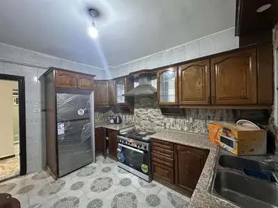 a kitchen with wooden cabinets and a stove top oven at Beautiful apartment in Irbid