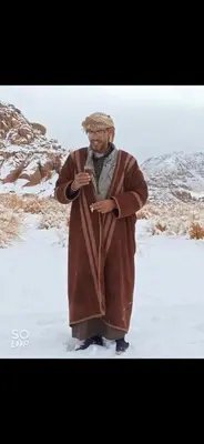 a man standing in the snow wearing a brown robe at Wadi Rum Hiking &camp in Wadi Rum