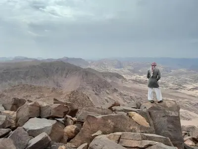 a man standing on a rock in the desert at Wadi Rum Hiking &camp in Wadi Rum
