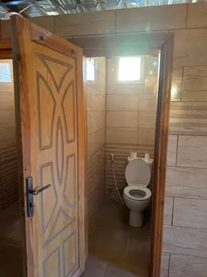 a bathroom with a toilet with a wooden door at Desert Star Camp in Wadi Rum
