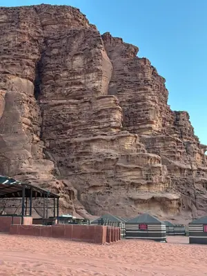 a large rocky mountain with a building in front of it at Desert Star Camp in Wadi Rum