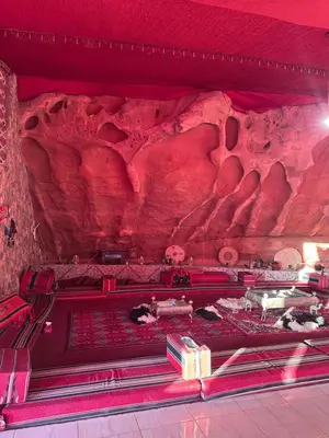 a room with a red wall with a rock formation at Desert Star Camp in Wadi Rum