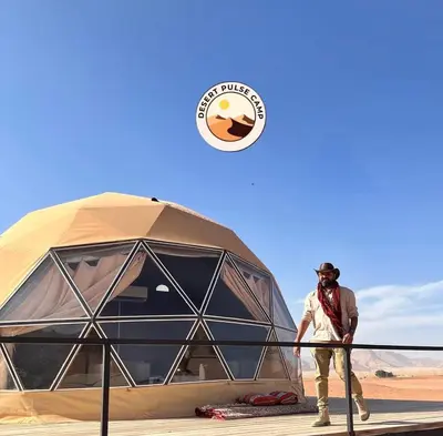 a man standing next to a tent in the desert at RUM BULSE BUBBLE lUXURY CAMP in Disah