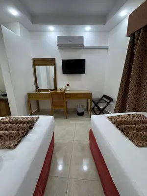 a room with two beds and a desk and a television at Petra Rocks Hotel in Wadi Musa