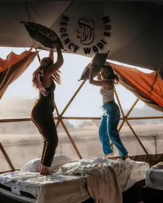 two girls are standing on top of a bed at Regency Bubble Wadi Rum in Wadi Rum