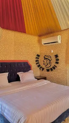a bedroom with a bed with a sign on the wall at Regency Bubble Wadi Rum in Wadi Rum