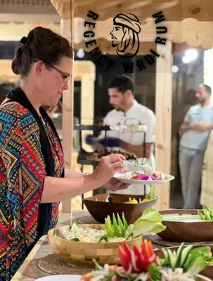 a woman holding a plate of food at a buffet at Regency Bubble Wadi Rum in Wadi Rum